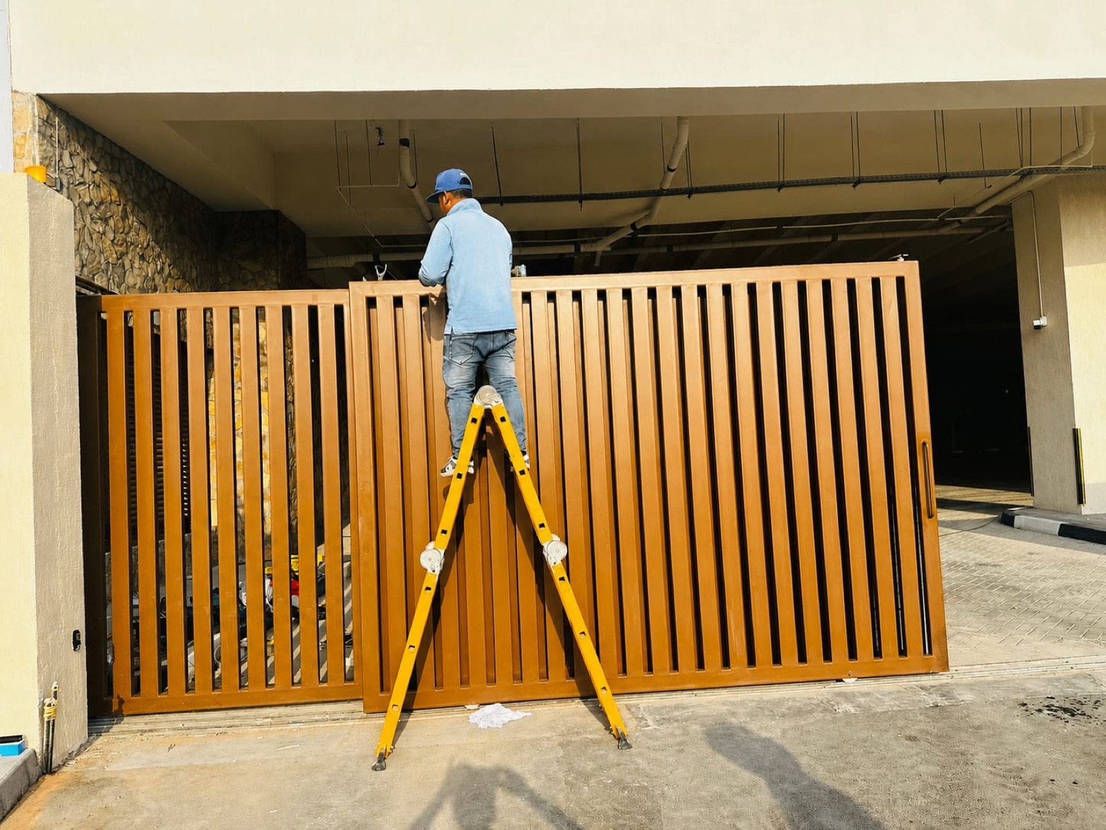 Wood-slat modern sliding entrance gate installation at Dubai villa