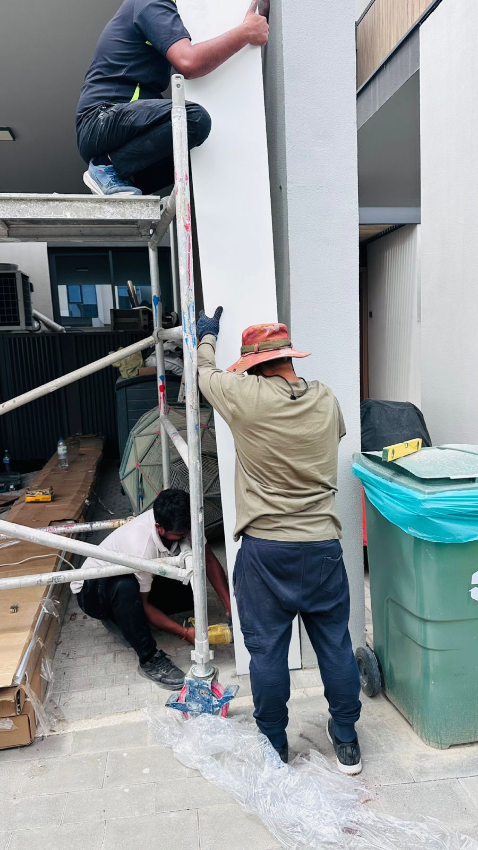 Three technicians installing sectional garage door at modern Dubai villa