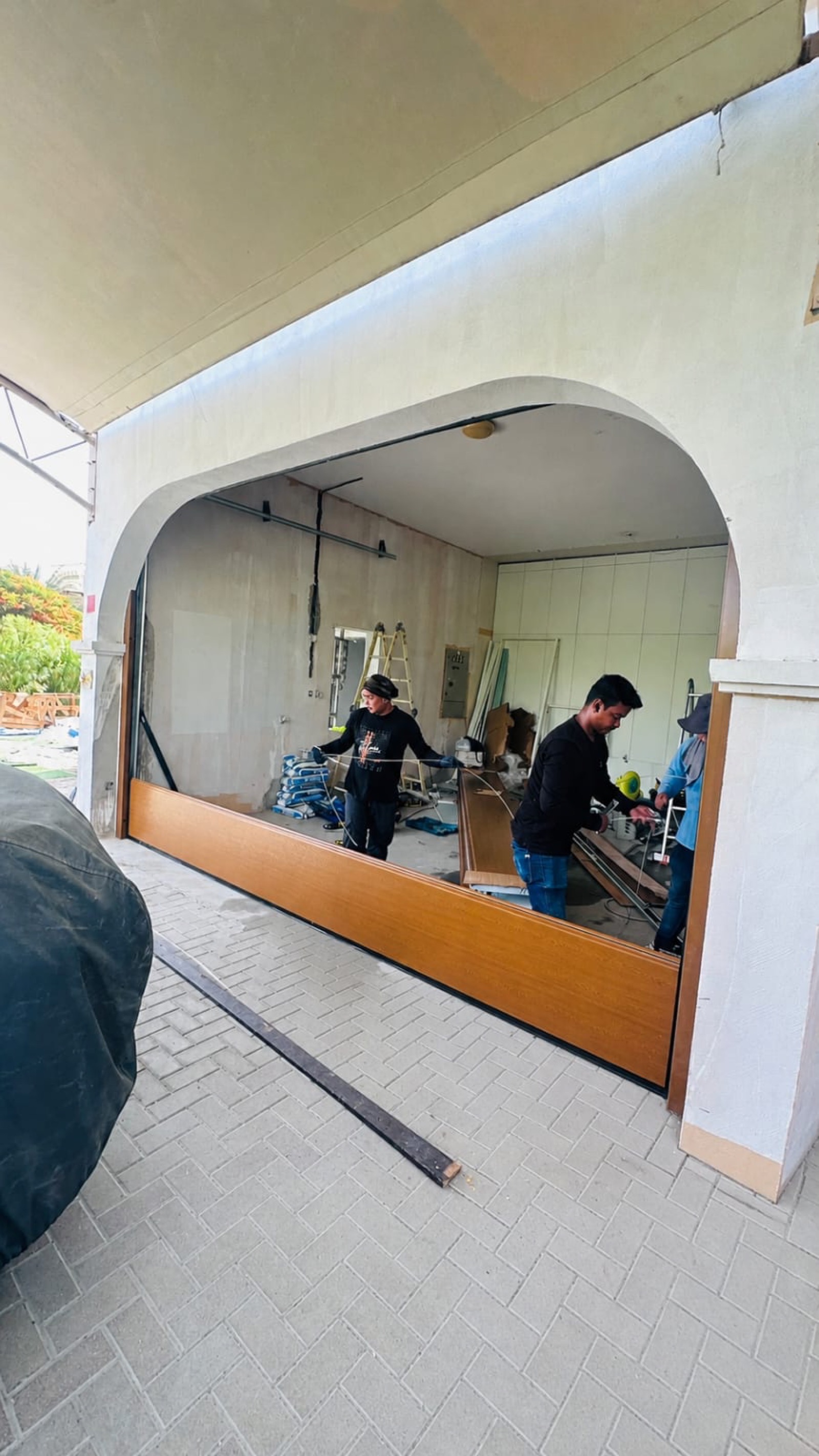 Wood-grain composite garage door installation on Spanish-revival villa in Dubai