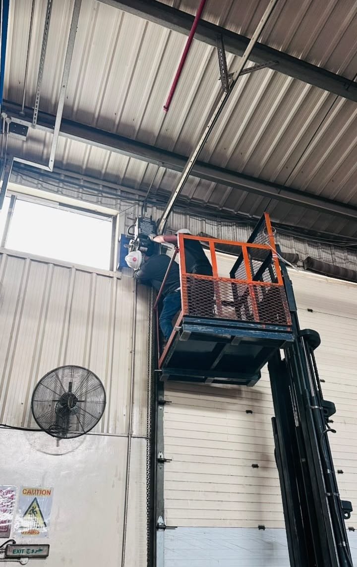 Technician on aerial lift servicing high-speed door motor at Dubai warehouse