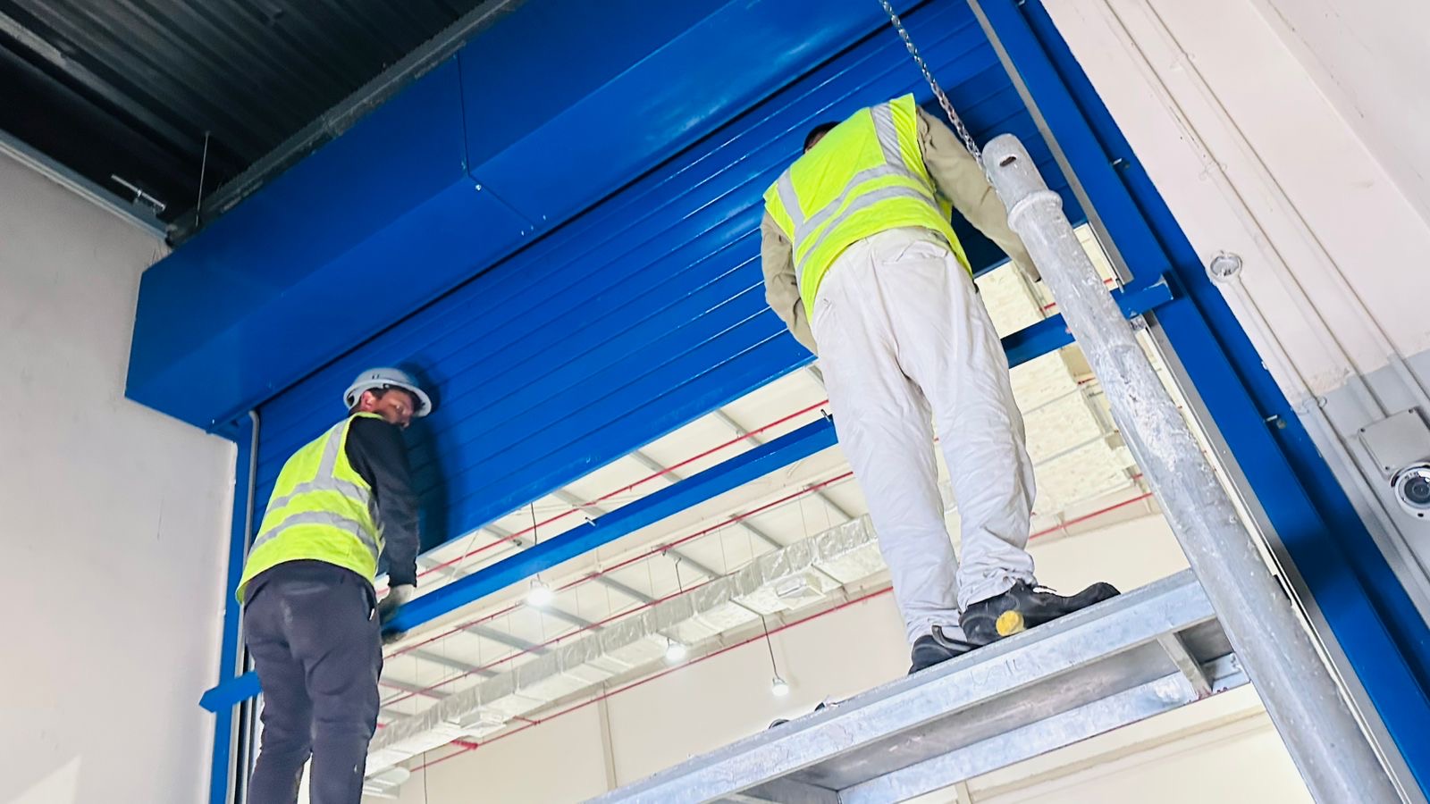Blue high-speed industrial roller door installation in Dubai warehouse