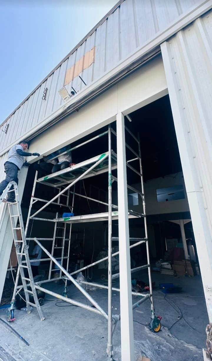 Team installing industrial door with scaffolding at Dubai warehouse