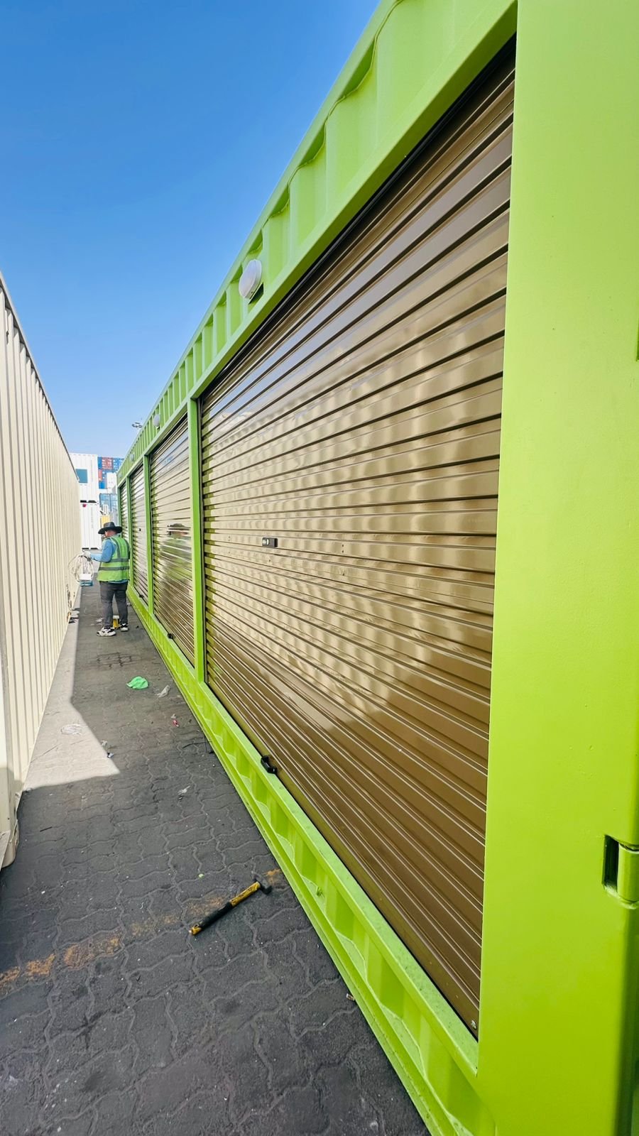 Row of bronze rolling shutters across green containers in Dubai